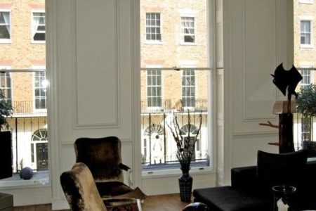 Interior view showcasing secondary glazing installation with large windows, stylish furniture, and decorative plants, enhancing home aesthetics and functionality.