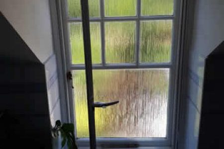 Slimline hinged panel window with frosted glass, suitable for secondary glazing in bay windows, showcasing natural light and green outdoor view.